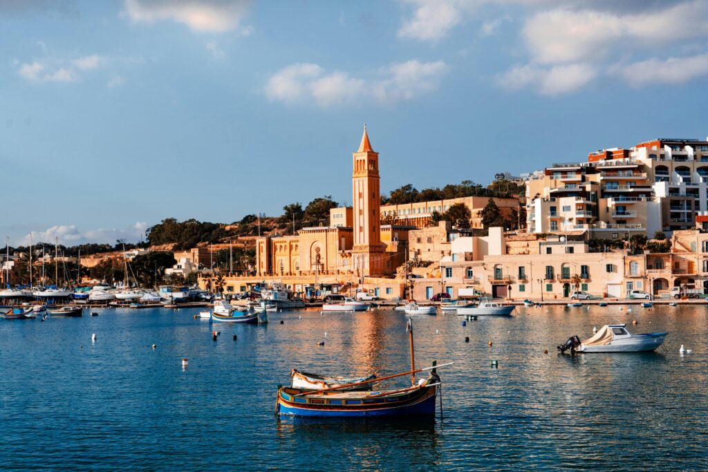 Breathtaking view of Marsaskala harbor with traditional boats and historic buildings in sunny Malta.